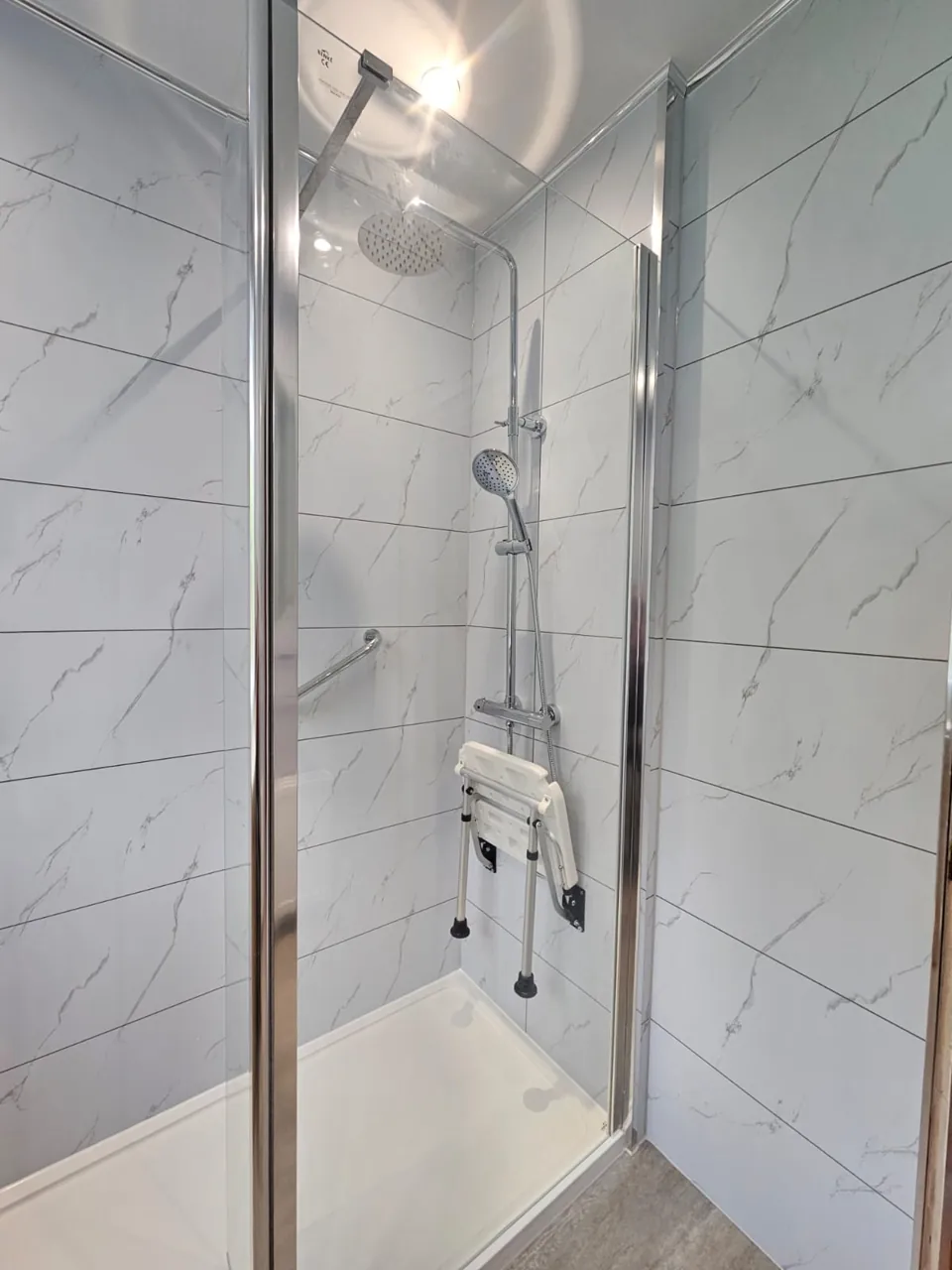 Shower enclosure with marble-effect walls and folding seat